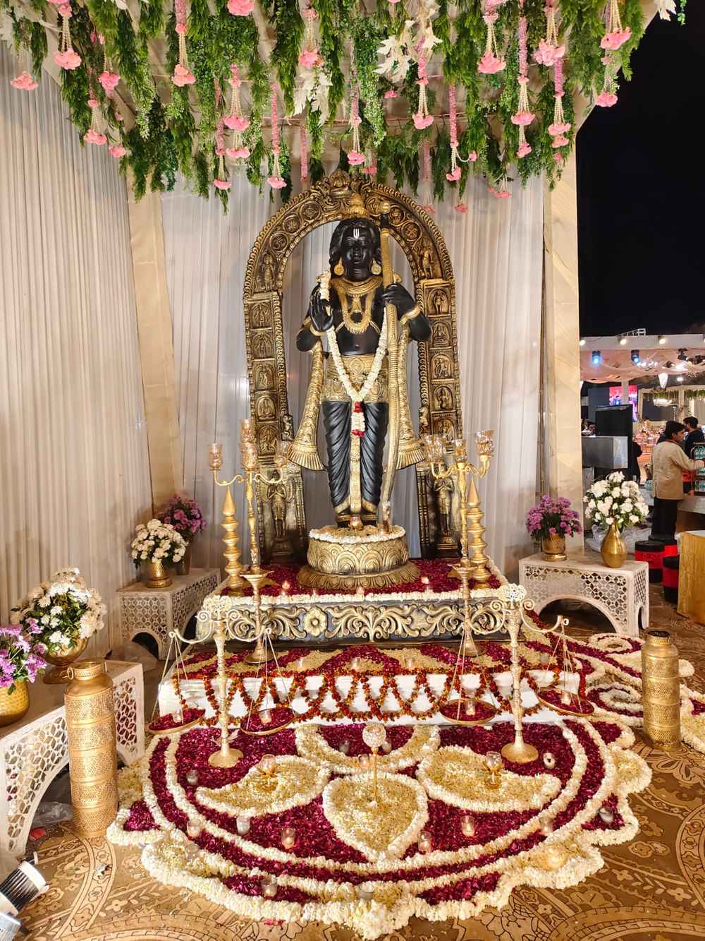 Black and gold deity altar with floral rangoli