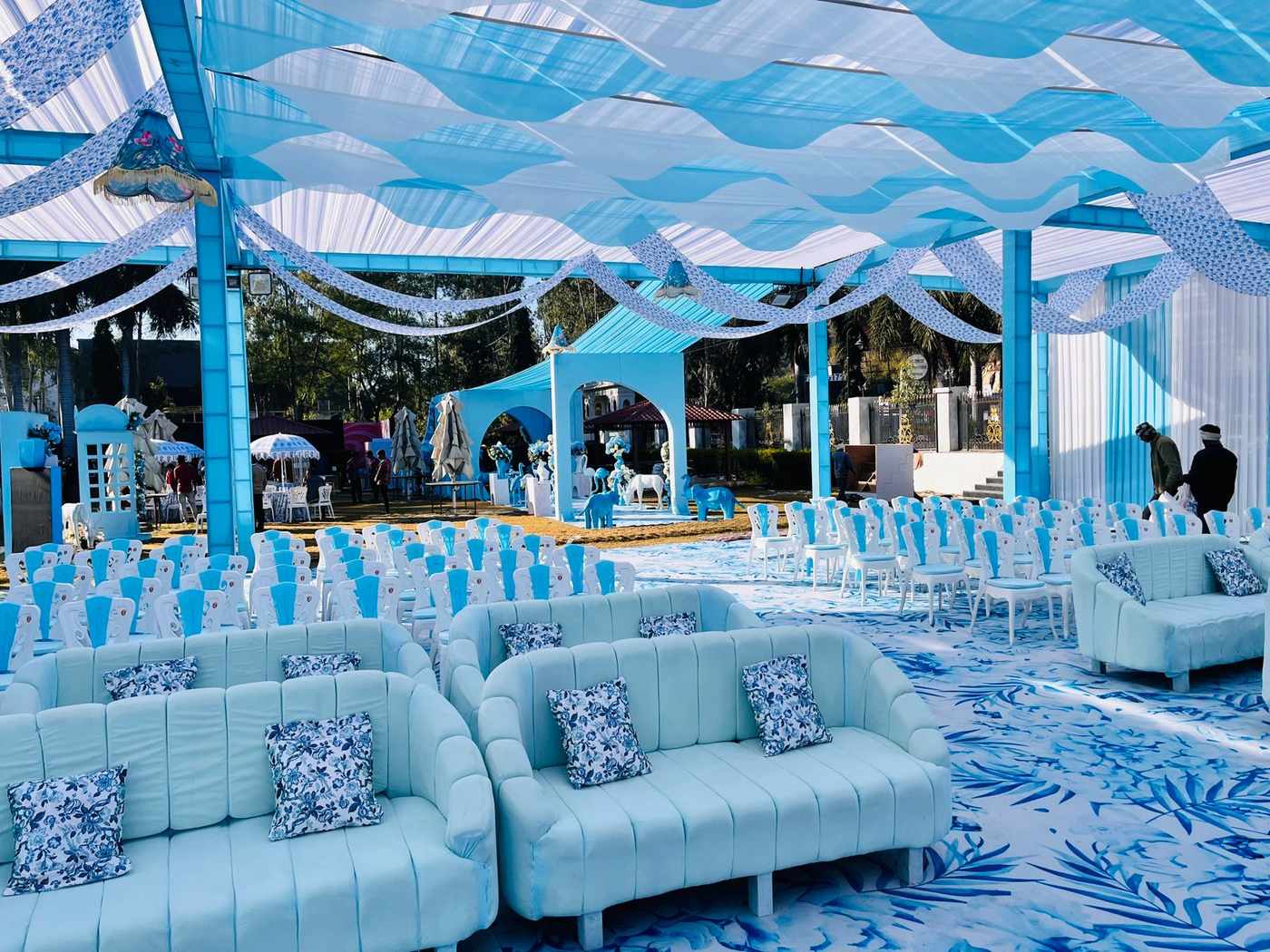 Blue outdoor wedding setup with white seating