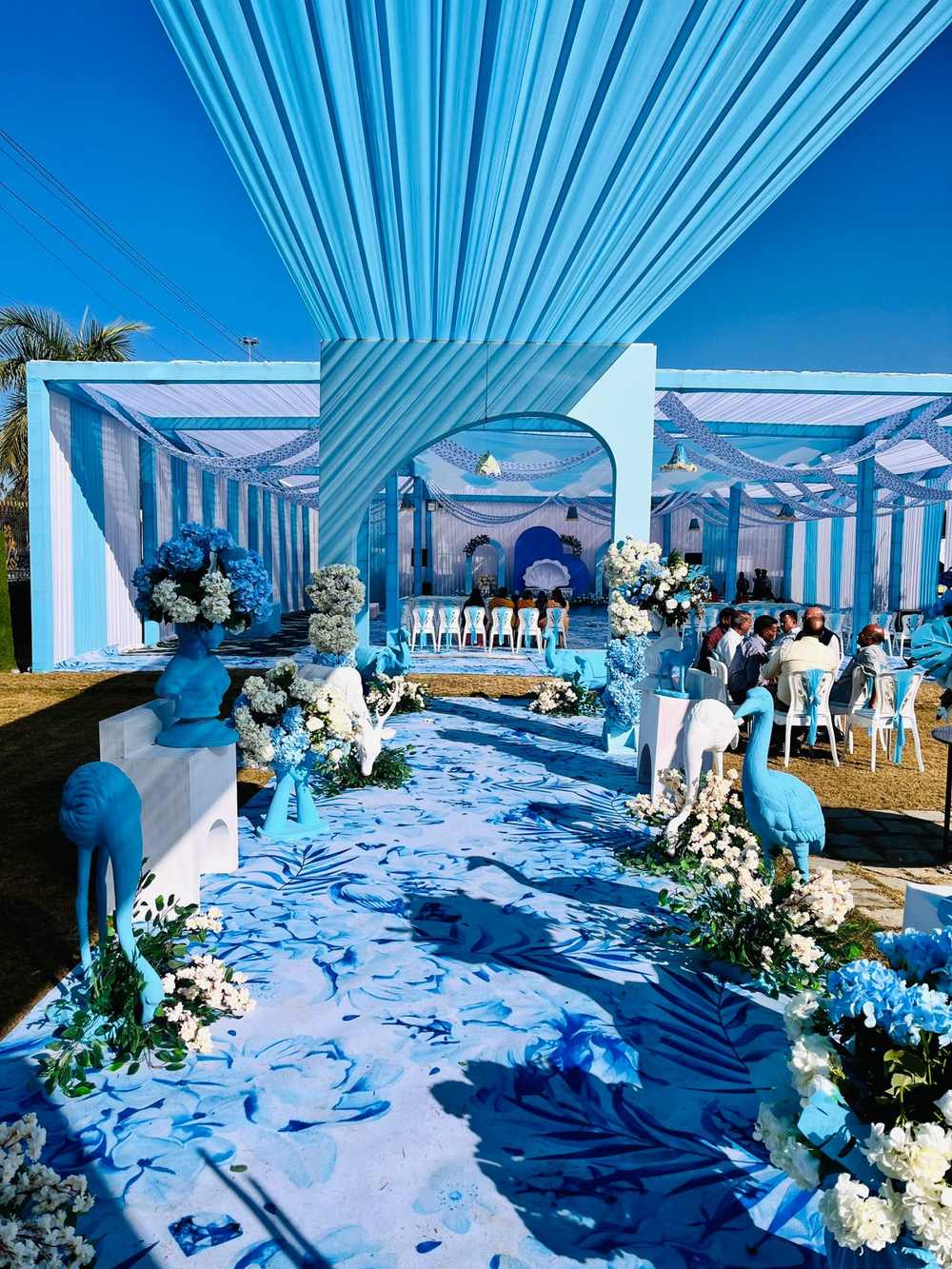 Blue and white outdoor wedding venue with peacock details