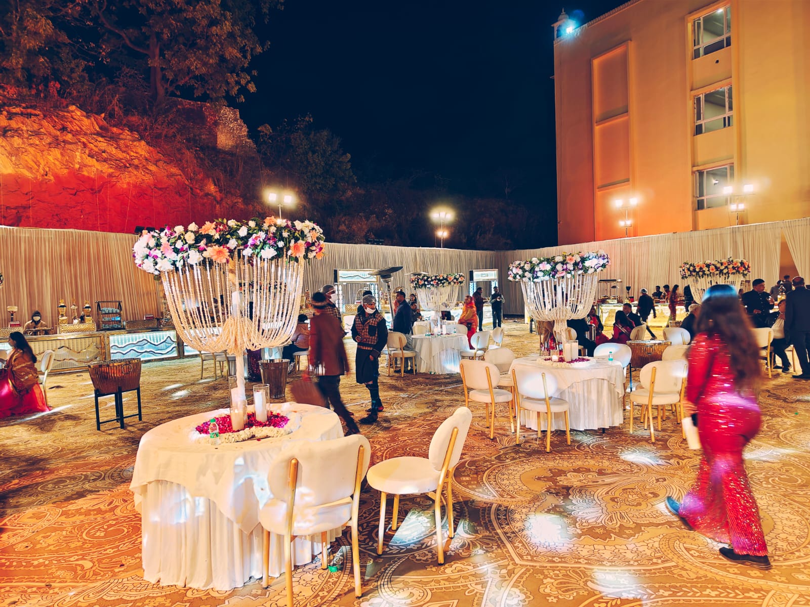 Outdoor wedding reception at night with chandeliers and round tables